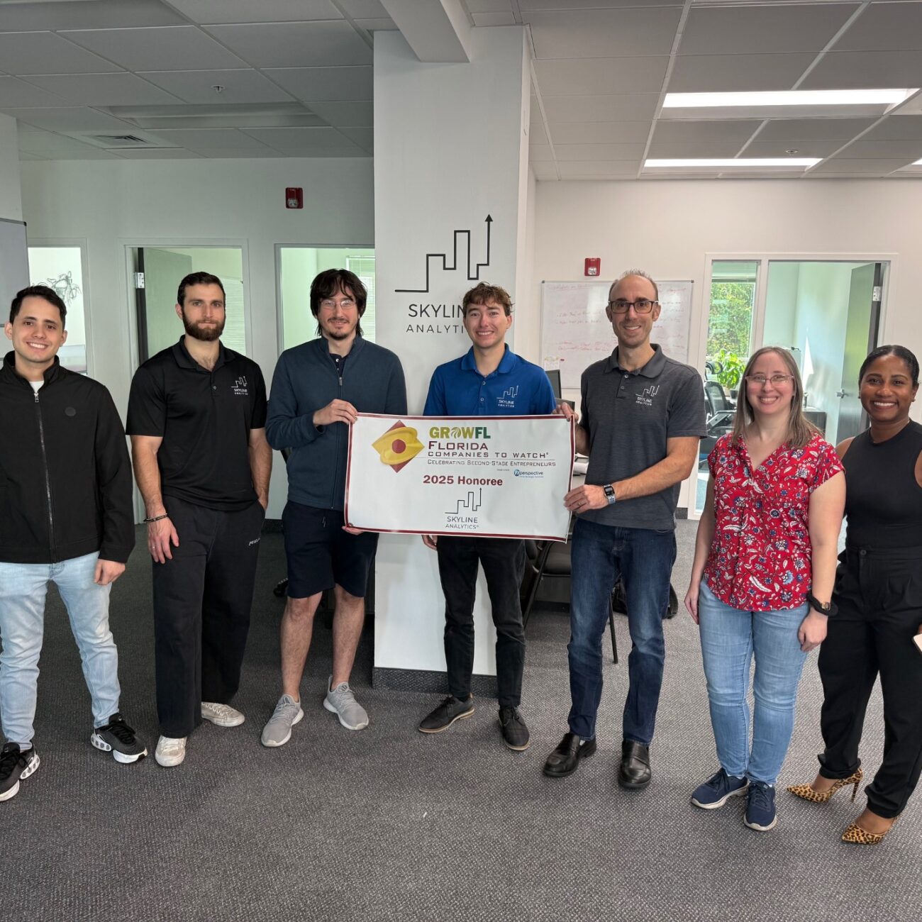 The Skyline Analytics team standing in front of a GrowFL Florida Companies to Watch banner