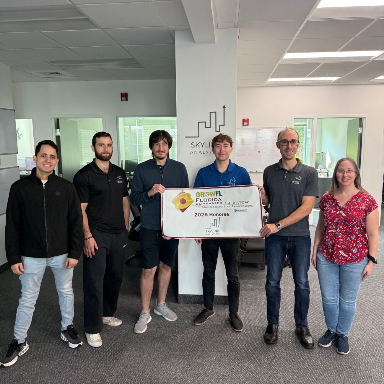 The Skyline Analytics team standing in front of a GrowFL Florida Companies to Watch banner