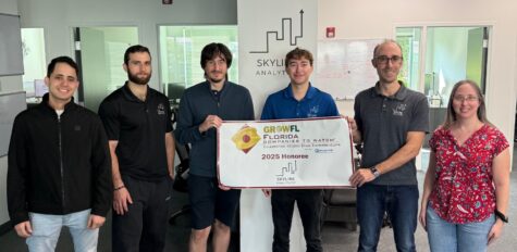 The Skyline Analytics team standing in front of a GrowFL Florida Companies to Watch banner