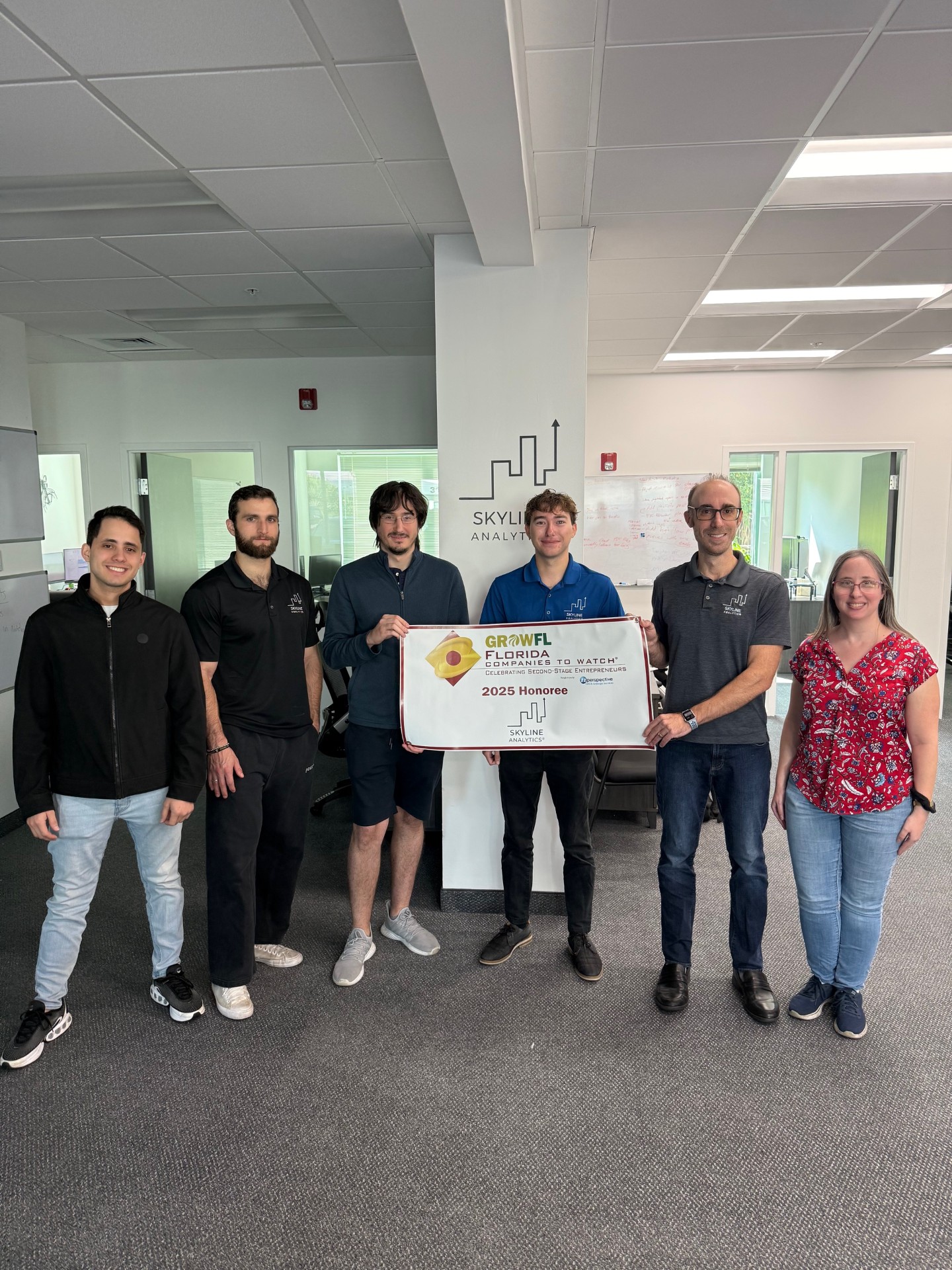 The Skyline Analytics team standing in front of a GrowFL Florida Companies to Watch banner