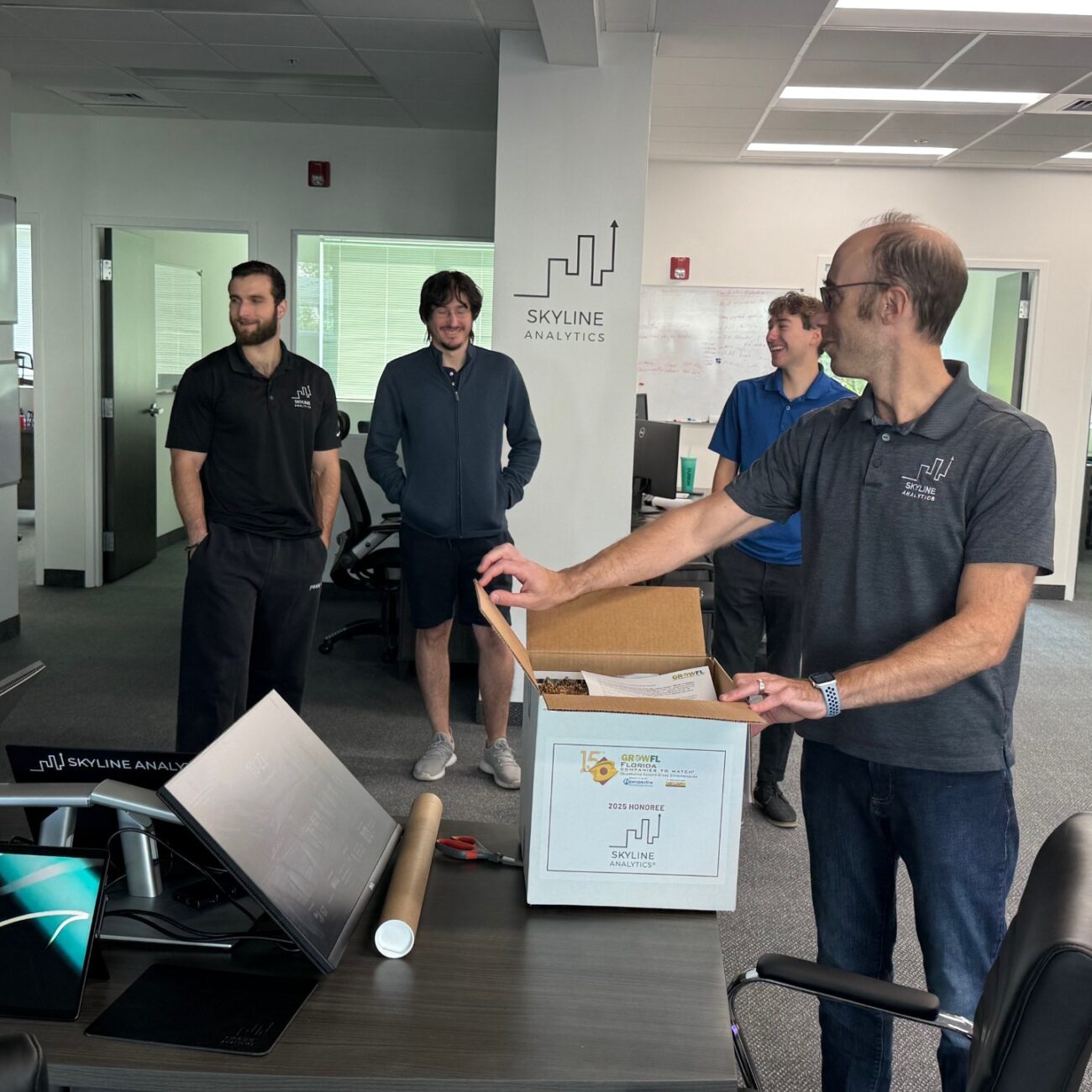 The Skyline Analytics team and Chris Pumo, CEO unboxing the GrowFL Florida Companies to Watch celebration box